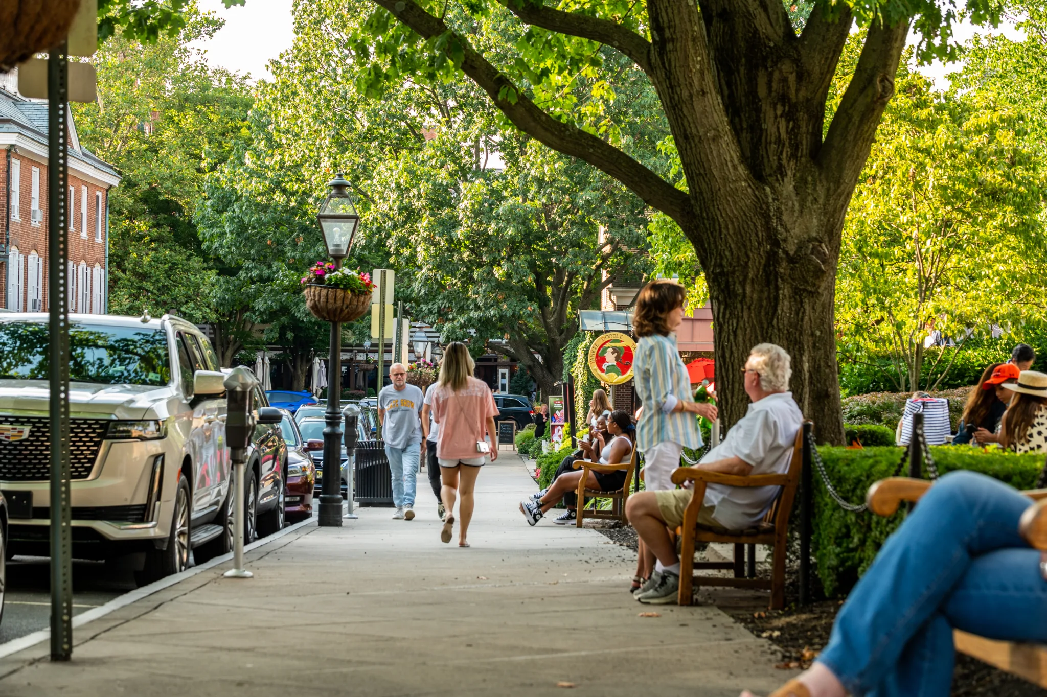 People walking along a tree-shaded Palmer Square sidewalk